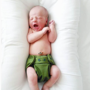 baby in a cloth diaper with umbilical cord attached at belly button